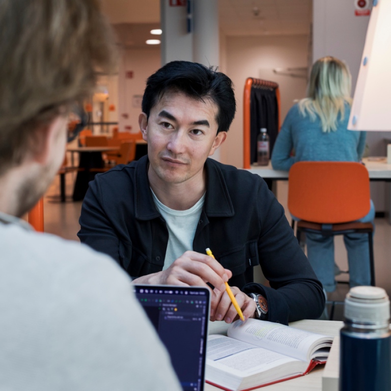 Två manliga studenter pluggar vid ett skrivbord