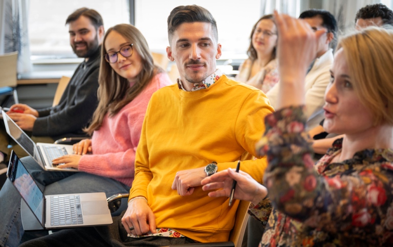 Studenter sitter i rader på seminarium. En pratar och gestikulerar.