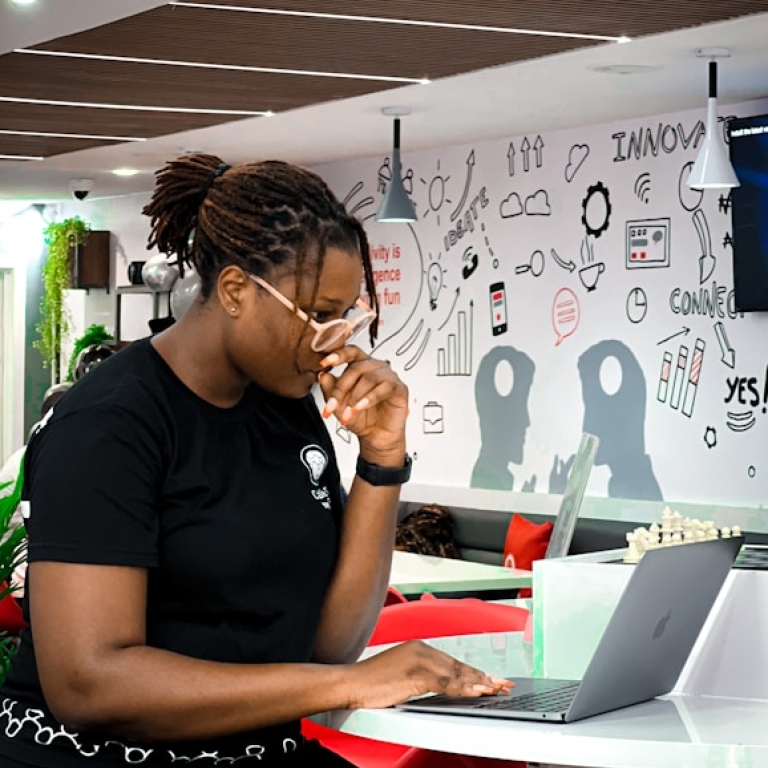Woman working on a laptop in front of a whiteboard