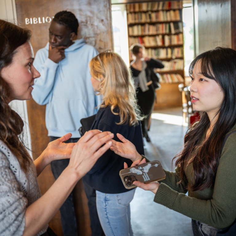 Students standing talking outside of a seminar room.