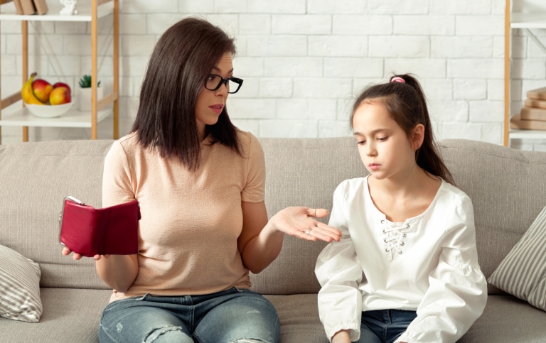 Mother and daughter sitting in a sofa discussing lack of money.