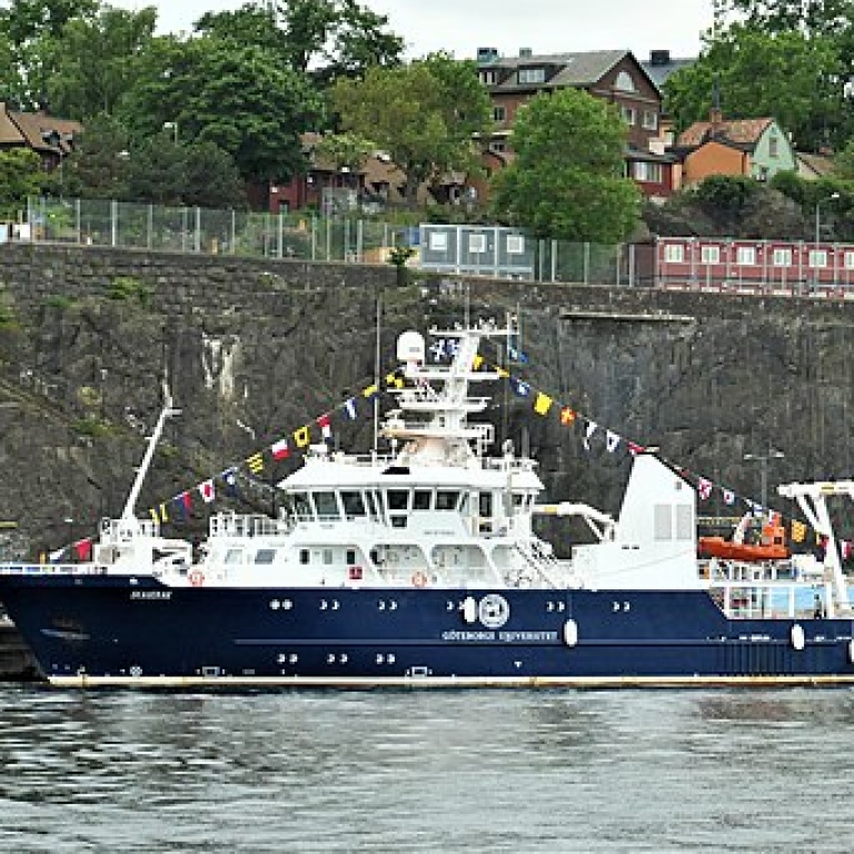 R/V Skagerak vid Stadsgårdskajen. I bakgrunden en klippvägg, gamla och moderna hus, grönska.