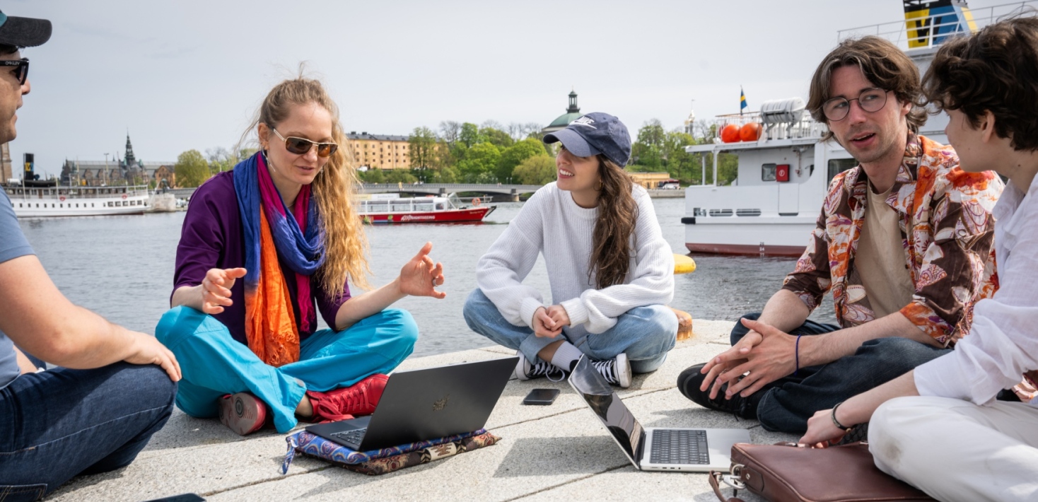 Students studying in the sun by the water.