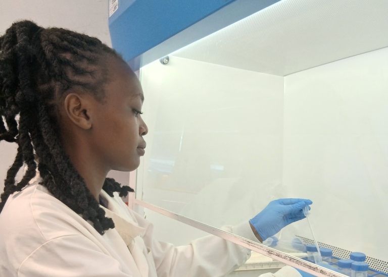 Woman in a lab couat at a fume cupboard.
