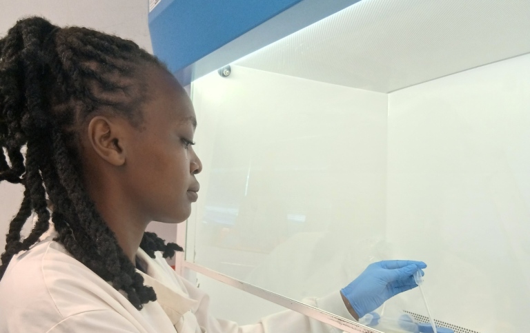 Woman in a lab couat at a fume cupboard.