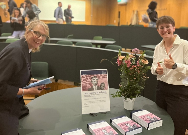 Sofia och Marie står vid ett bord med blommor och exemplar av Sofias avhandling.
