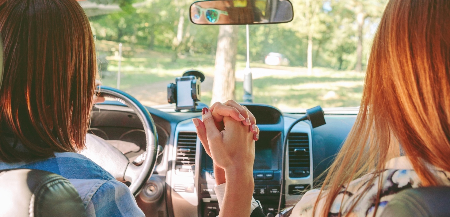 Two women in a car holding hands.