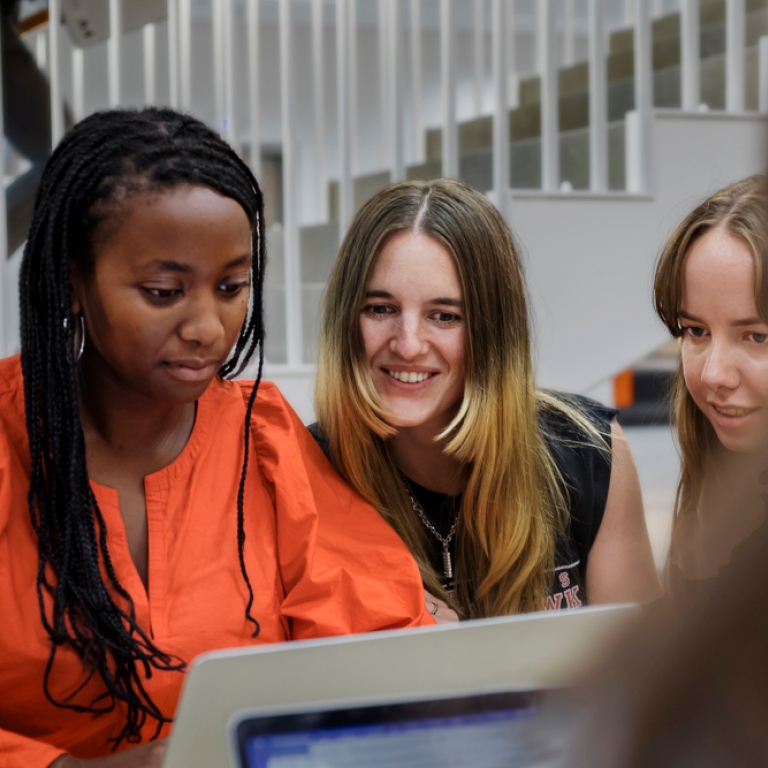 Three students in front of a computer.