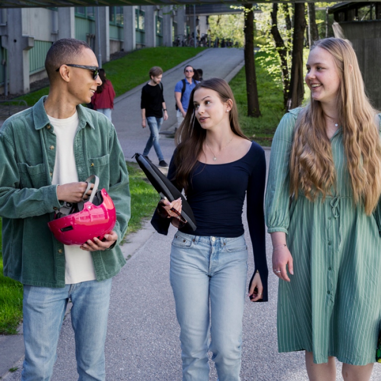 Tre studenter går ute på universitetsområdet.