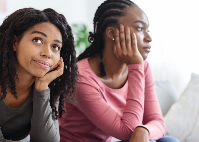 Two sad african american women sitting on a sofa