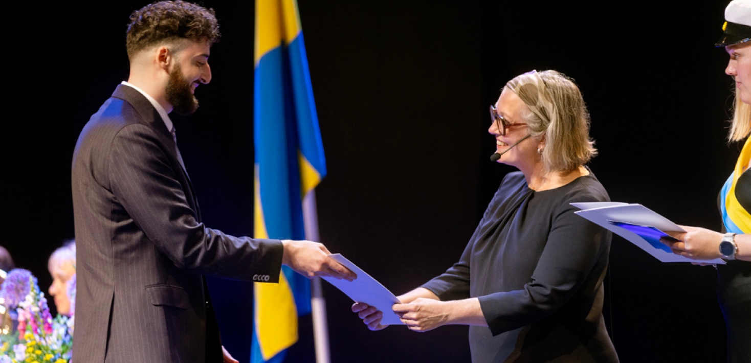 Promotor för Juridiska fakulteten överräcker diplom till nyexaminerad student