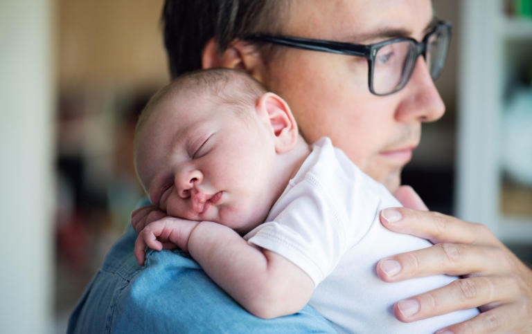 Close up of young father holding his newborn baby son in his arms.
