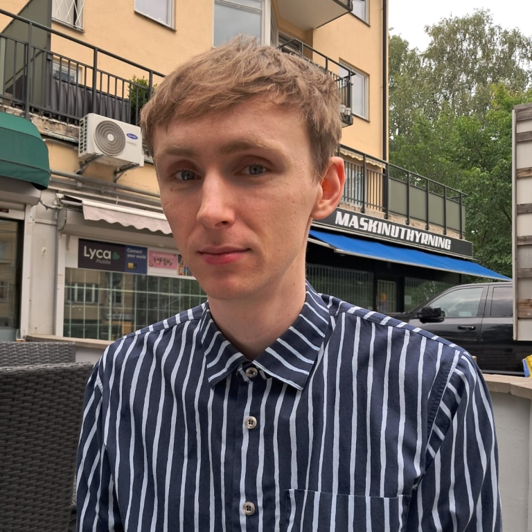 Man med ljust kortklippt hår och blåvitrandig skjorta