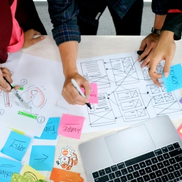 Flera personer samarbetar i en designprocess med post-it-lappar och dator.