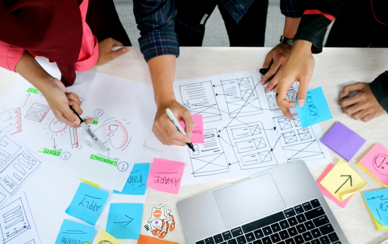 Several people working together in a design process, with post-it notes and a computer.