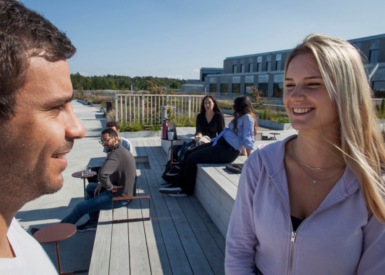 Kvinnliga och manliga studenter som pratar med varandra.