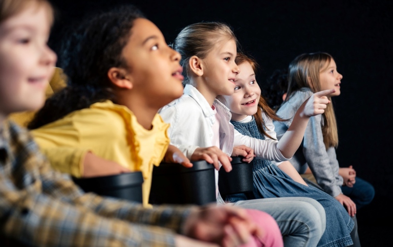 Barn sitter i en publik och tittar engagerat på film.