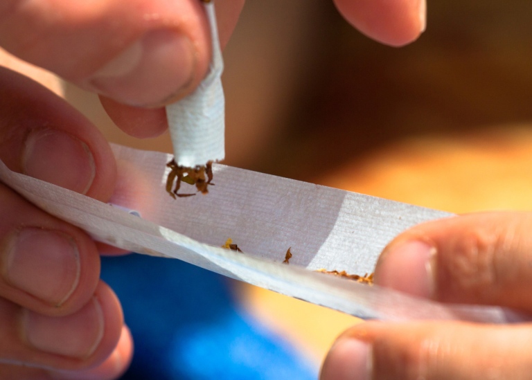 Close-up of a man’s fingers as he rolls a joint.