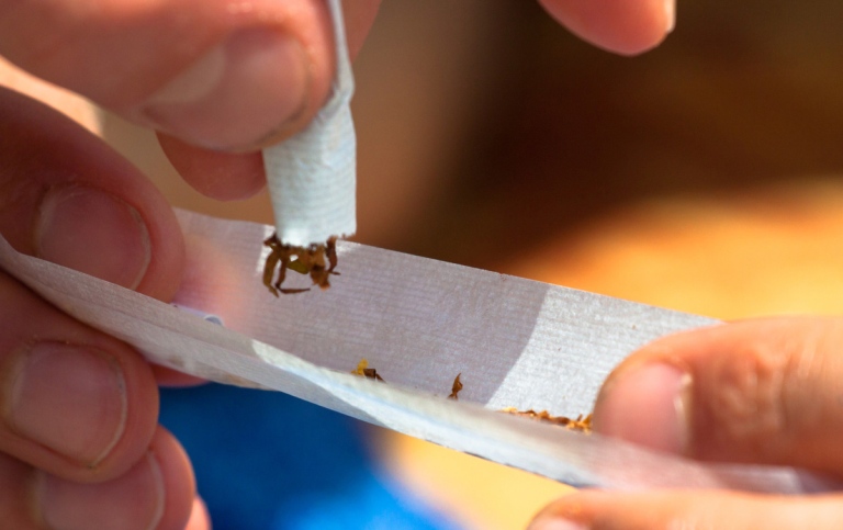 Close-up of a man’s fingers as he rolls a joint.