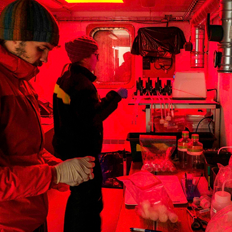Red light, lab equipment, two persons filtering water.
