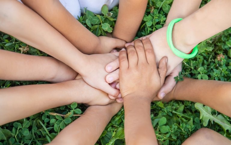 Children´s hands, joined together on a background of grass.