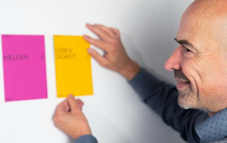 Man sätter upp postit-lappar på en tavla.