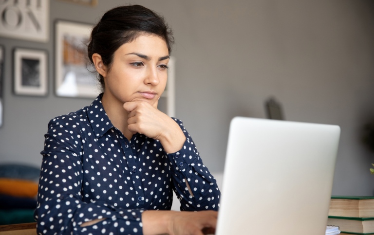 Kvinna som tänker vid datorn.
