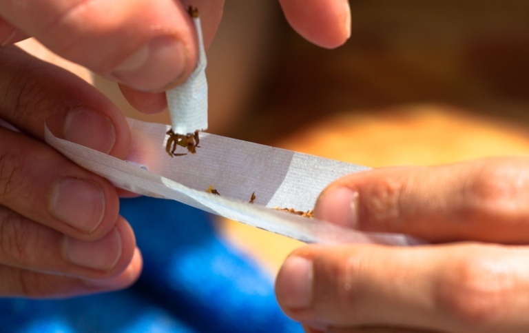 Närbild av fingrar som rullar en joint.