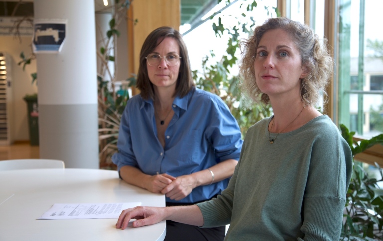 two women sitting at a white table facing the camera