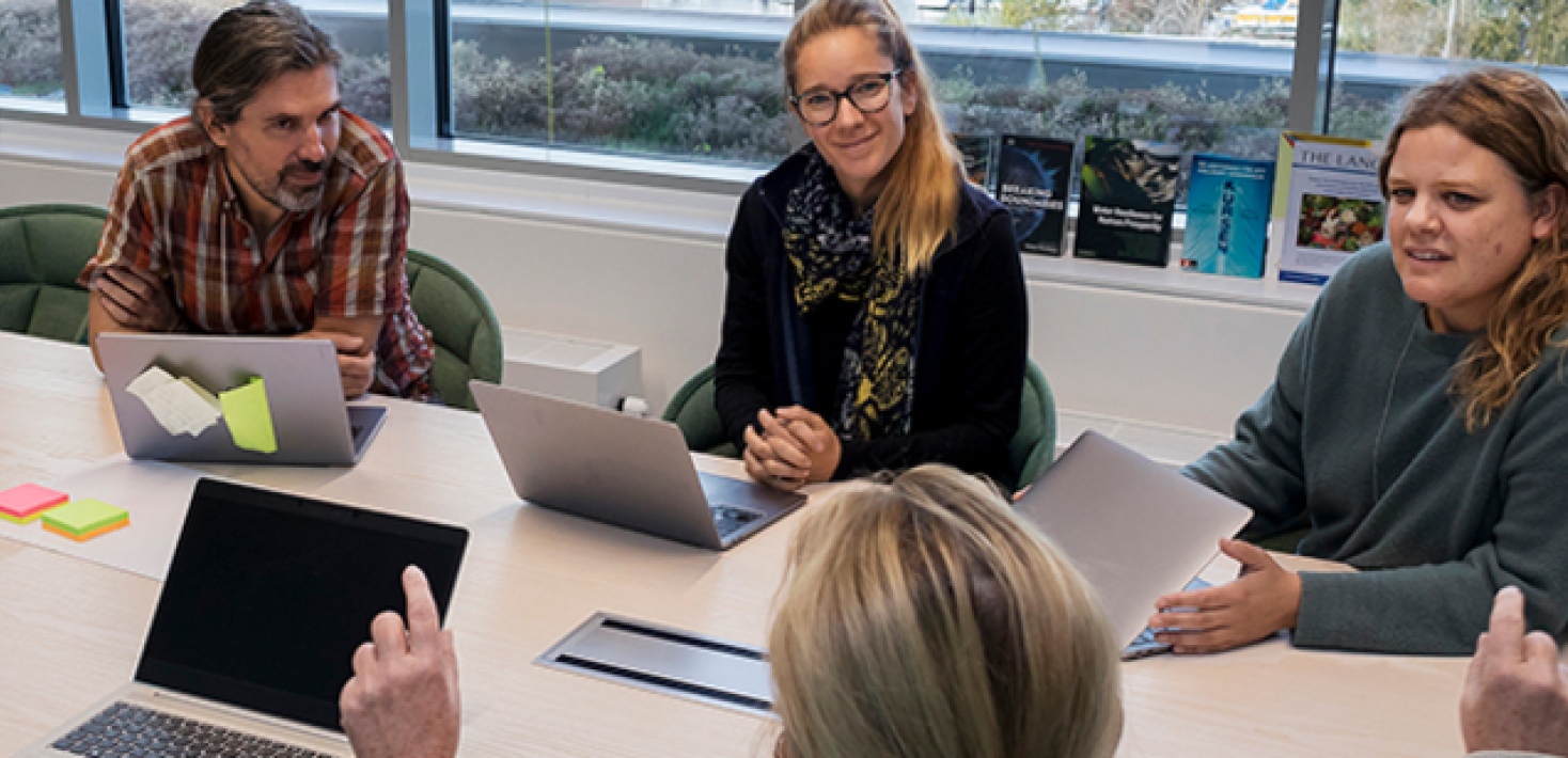 Medarbetare sitter runt konferensbord.