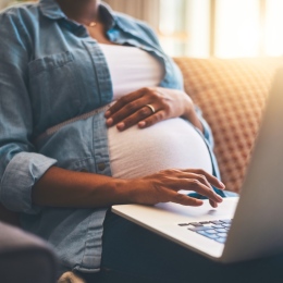 Gravid kvinna skriver på dator