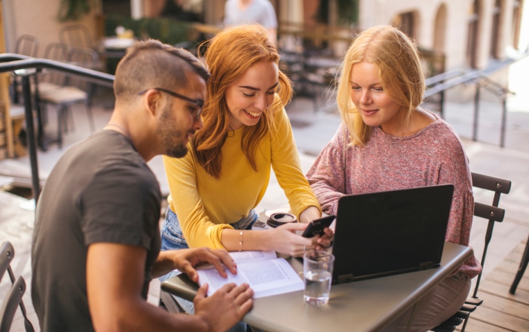 Three students studying at an outdoor café.