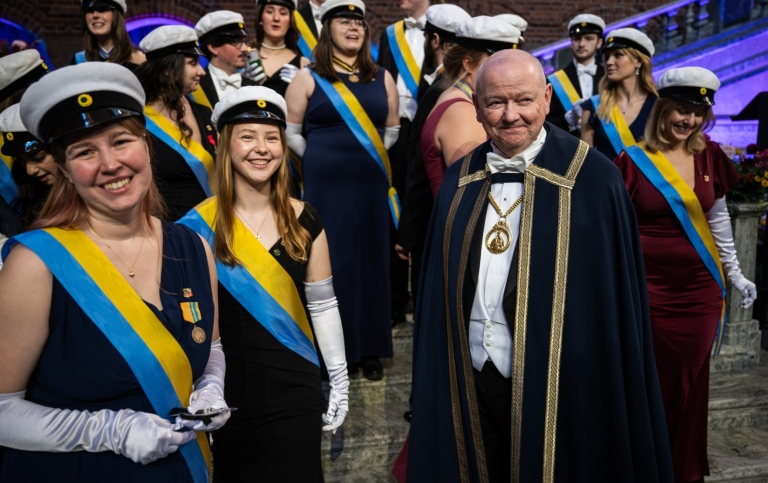 Rektor Hans Adolfsson tillsammans med studenter i studentmössor.