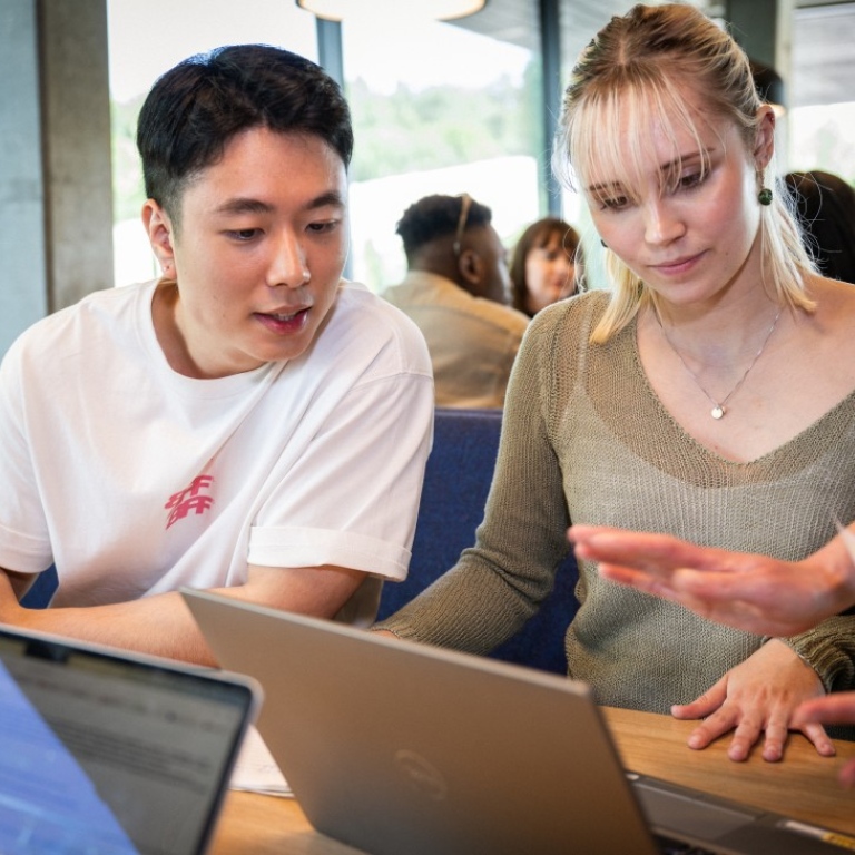 studenter diskuterar med varandra framför dator