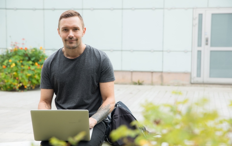 Man med laptop utomhus.