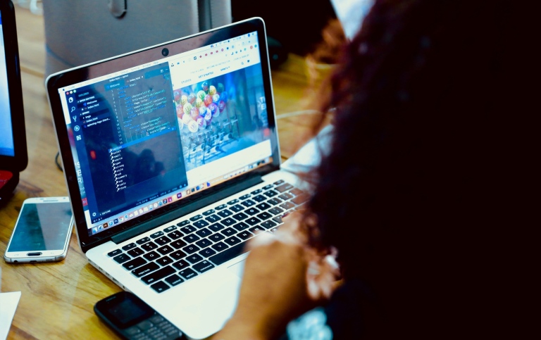 A person working at a computer, screen is full of code.