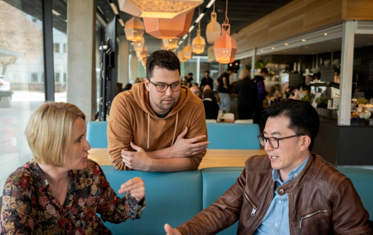 Tre personer diskuterar i cafét i Studenthuset.