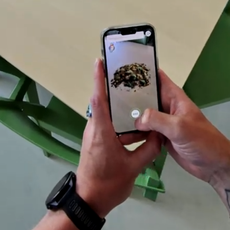 Händer som håller i en mobil där appen för studien är igång.