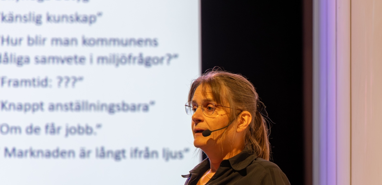 En kvinna med glasögon vid en talarstol