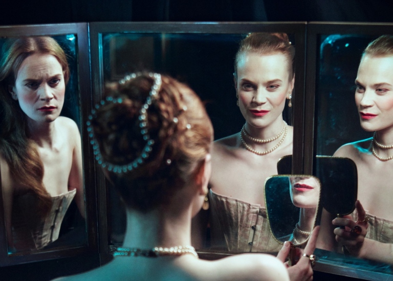 En kvinna ser på sig själv i flera speglar.