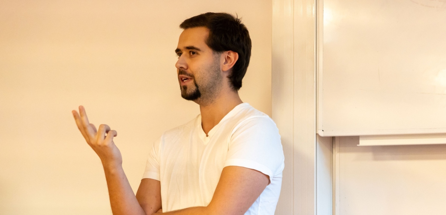 Martin has dark hair, a beard, and a moustache