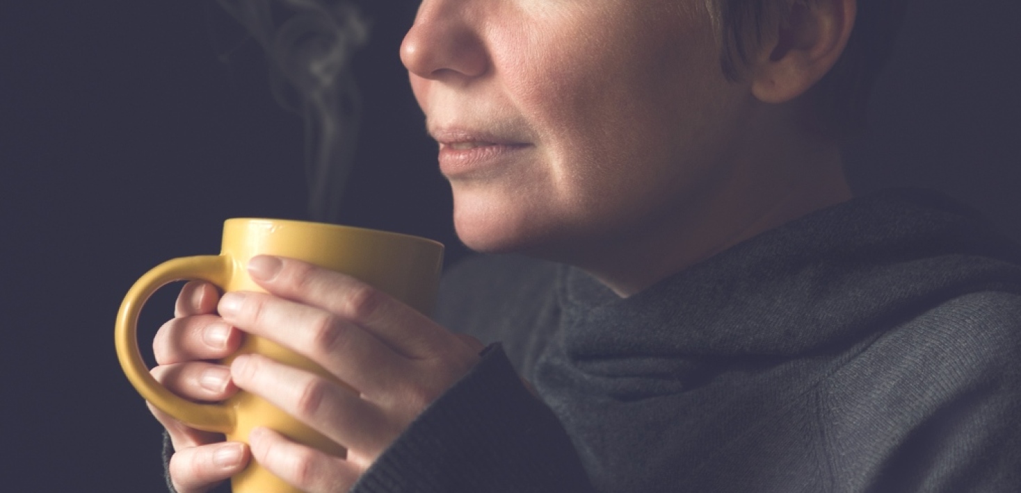 Person med kopp i händerna som luktar på kaffe