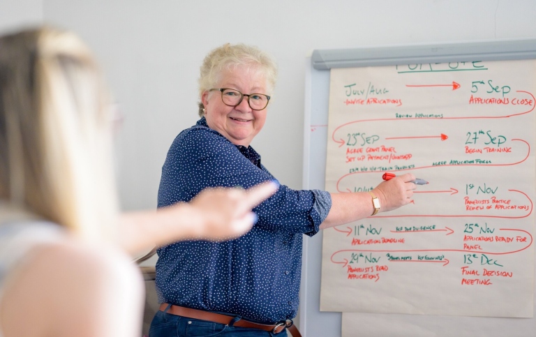 Elderly woman working with younger woman in an office.