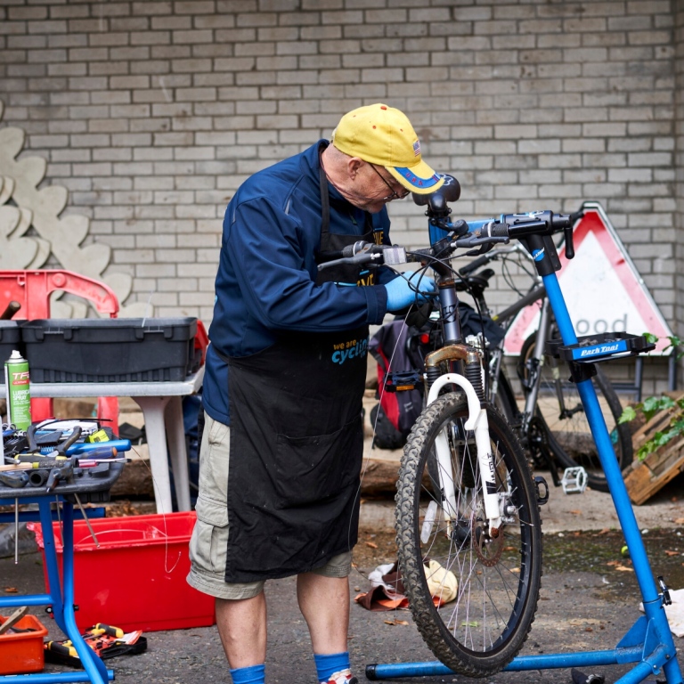 Elderly man working on a bicycle.