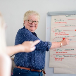 Äldre kvinna jobbar med en yngre framför ett blädderblock.