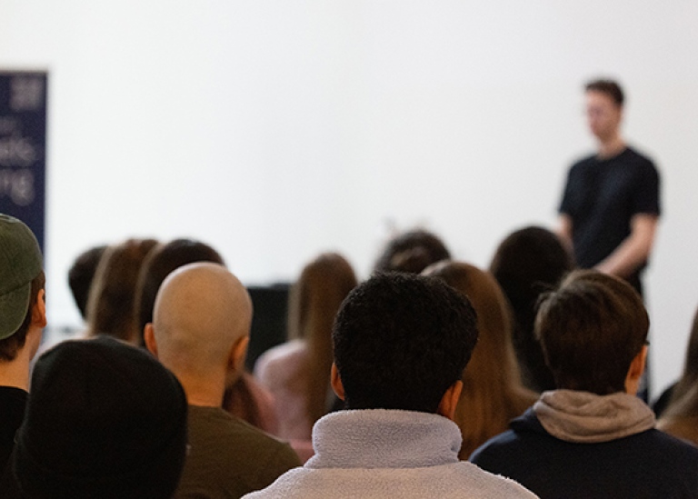 Föreläsare står framför en publik.