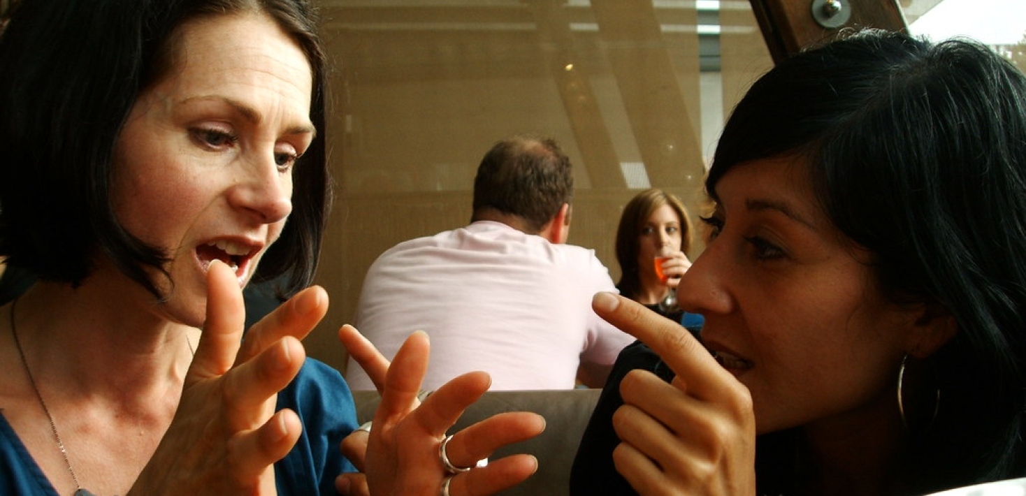 Two women facing each other and discussing with gestures.