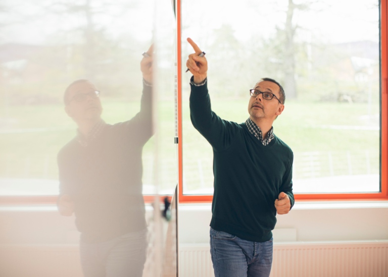 Lärare i klassrum, pekar på en undervisningstavla.