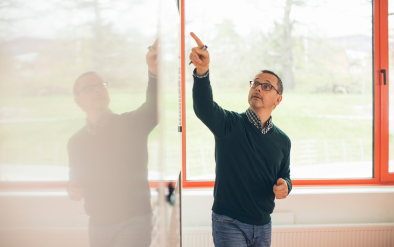 Lärare i klassrum, pekar på en undervisningstavla. 