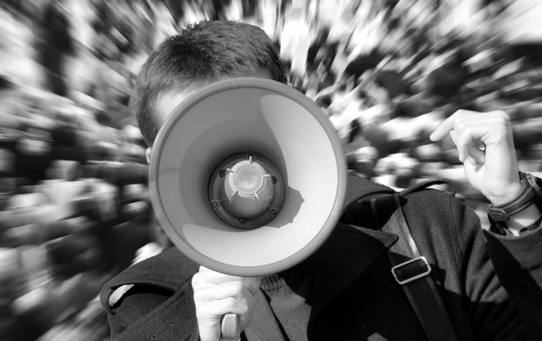 Person med megafon i närbild med tratten i fokus.